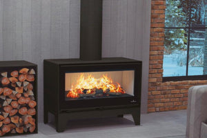 Bronpi - Cairo 90 - 16kW Freestanding Wood Burning Box Stove with flames between a log storage and a window showing snow outside