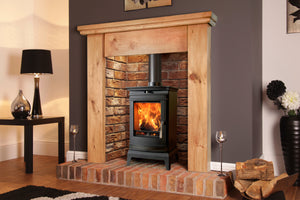 Portway - Rochester 5 - 5kW Wood Burning Stove with flames in a brick fireplace suit and brick hearth